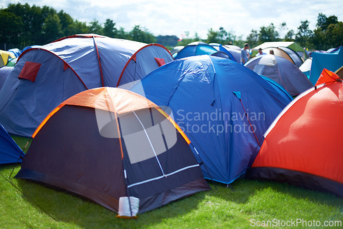 Image of Group, colourful and camping tents in nature outside of a music festival campsite. Row of canopies placed on ground at musical concert, entertainment event and carnival celebration outdoor on grass