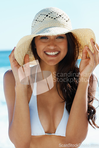 Image of Woman, hat and smile at beach in portrait, nature and traveling to ocean for peace on vacation. Female person, outdoors and calming water on summer holiday, getaway and relaxing on tropical island