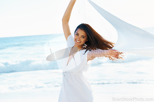 Image of Woman, sea and portrait with fabric in wind with smile for freedom, adventure and relax in nature by waves. Girl, person and happy with cloth on holiday, vacation and outdoor by ocean in Indonesia