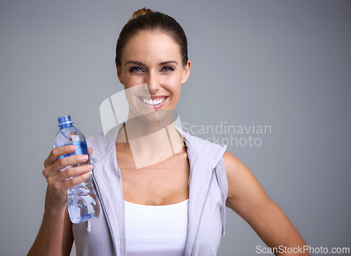 Image of Fitness, portrait and happy woman with water in studio for training, wellness or detox on grey background. Sports, bottle and face of female model with liquid hydration for body workout recovery