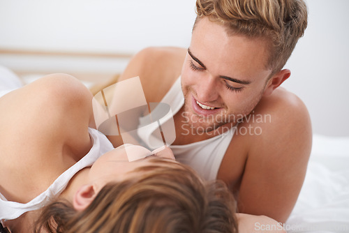 Image of Couple, love and lying in bed with happiness and care for conversation with partner. Husband, smile and connection with wife on communication and discussion for marriage in bedroom and house