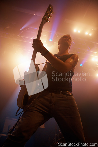 Image of Concert, rock and guitar with man on stage for music, performance and band show. Event, spotlight and energy with male musician playing instrument at festival club for rave, disco and celebration