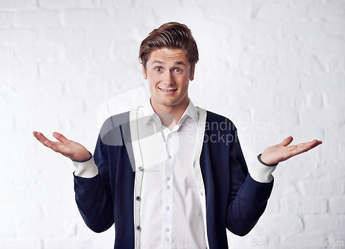 Image of Confused, shrug and portrait of man with doubt on wall background for choice, option and decision. Facial expression, thinking and isolated person with unsure, question and wonder reaction in studio