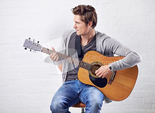 Image of Man, guitar and musician with art and music, acoustic for entertainment and performance against wall background. Busker, artist and musical instrument for creativity, track or song with talent