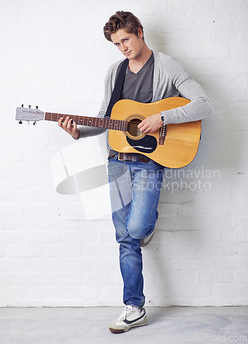 Image of Man in portrait, guitar and musician with creativity and music, acoustic for entertainment and performance on wall background. Busker, artist and musical instrument for art, track or song with talent