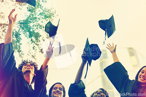 Image of Happy group, students and hats in celebration for graduation, winning or achievement at campus. People or graduates throwing caps in air for certificate, education or milestone at outdoor university