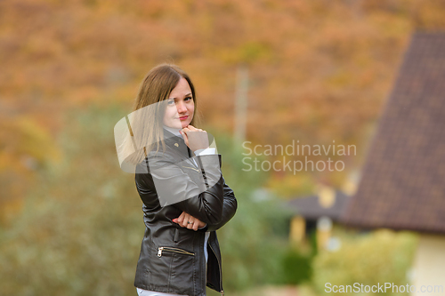 Image of Portrait of a young beautiful girl in casual clothes against the background of a blurred autumn forest, the girl smiles and looks into the frame