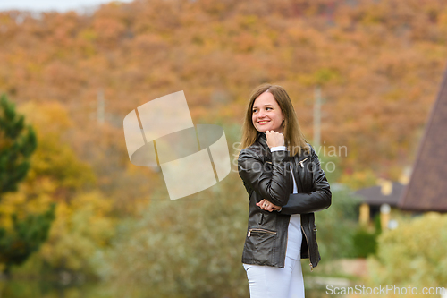 Image of Portrait of a young beautiful girl in casual clothes against the background of a blurred autumn forest, the girl smiles and looks into the distance