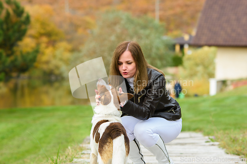 Image of A young beautiful girl caresses a dog, against the backdrop of a beautiful landscape