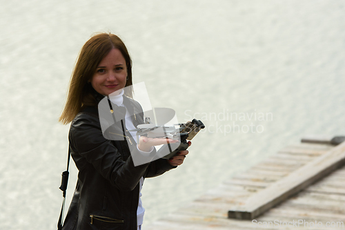 Image of A young beautiful girl launches a radio-controlled quadcopter on the shore of a lake, the drone landed on the girl's hand