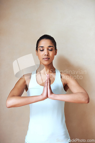Image of Meditation, eyes closed and woman in home in namaste pose for yoga, exercise and zen mindset. Calm, peaceful and person with prayer hands for wellness, mindfulness and workout on wall background