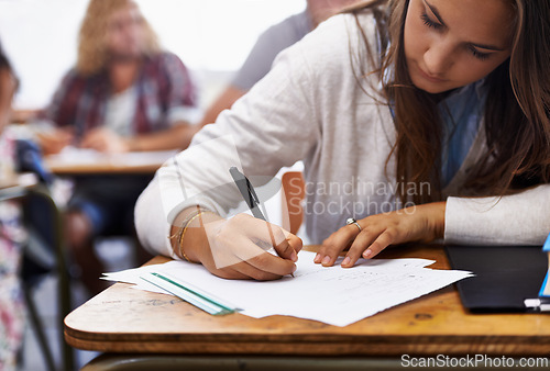 Image of University, classroom and woman writing exam at desk for education, knowledge and opportunity. College, learning and student with paper for test, assessment and studying with books, notes or report.