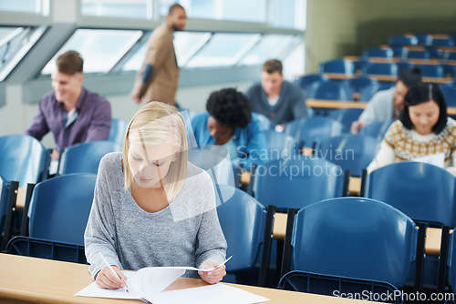 Image of Writing, university and woman student in classroom studying for test, exam or assignment. Education, scholarship and female person working on project with knowledge in lecture hall for learning.