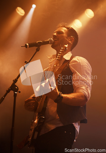 Image of Concert, singer and guitar with man on stage for music, performance and rock show. Event, spotlight and energy with male musician playing instrument at festival club for rave, disco and celebration