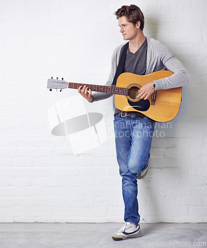 Image of Man, guitar and musician with creativity and music, acoustic for entertainment and performance against wall background. Busker, artist and musical instrument for art, track or song with talent