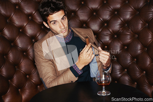 Image of Portrait, cigar and businessman smoking at pub, fashion and serious person in a suit with alcohol at vintage bar. Face, mafia and drinking whiskey, scotch and brandy in a glass for luxury at club