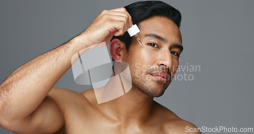 Image of Face, pipette and Asian man with skincare, oil and dermatology on a grey studio background. Portrait, Japanese person and model with wellness, treatment and grooming product with aesthetic and glow
