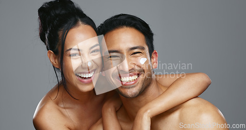 Image of Couple, smile and love for skincare, care and portrait with moisturizer in studio by gray background. Happy people, dermatology and hug for cosmetics, hydration and creme or love for skin treatment