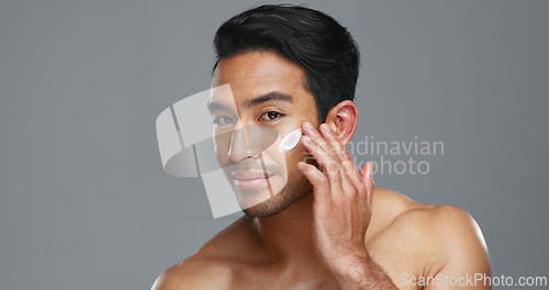 Image of Face, cream and man with skincare, cosmetics and dermatology on a grey studio background. Portrait, person and model with creme, beauty or luxury treatment with grooming, shine or glow with aesthetic