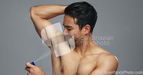 Image of Grooming, hygiene and man spraying armpit with perfume in studio, wellness and fragrance isolated on grey background. Deodorant, beauty and cosmetic product with body care, clean and fresh with skin