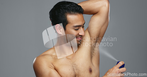 Image of Grooming, hygiene and man spraying armpit with perfume in studio, wellness and fragrance isolated on grey background. Deodorant, beauty and cosmetic product with body care, clean and fresh with skin