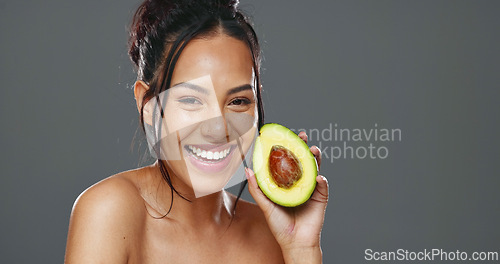 Image of Woman, avocado and beauty in studio for health, diet or smile on face for skincare by background. Girl, model or happy for fruit, nutrition choice or vegan food for wellness, natural glow or portrait