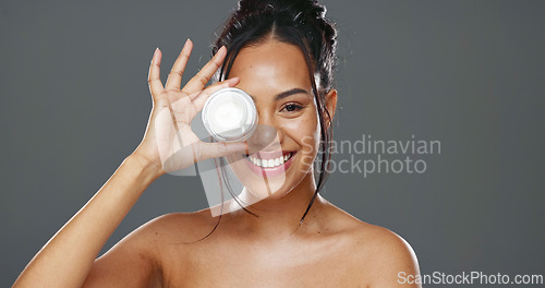 Image of Happy woman, face and cream for skincare, beauty or cosmetics against a grey studio background. Portrait of female person smile with moisturizer, creme or lotion for facial treatment or product