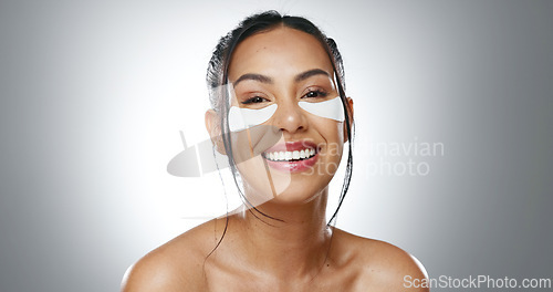 Image of Face, eye patches and woman with skincare, cosmetics and dermatology on a grey studio background. Portrait, person and model with beauty, treatment and healthy skin with grooming, smooth and shine