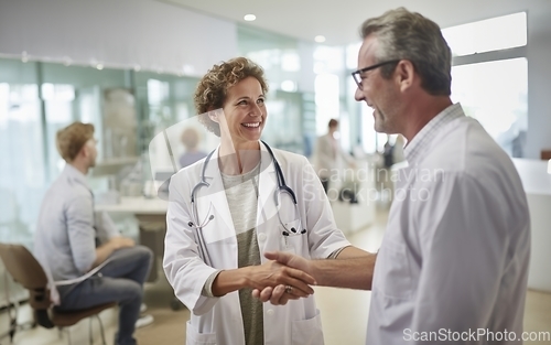 Image of In a modern hospital corridor, doctors exchange handshakes, reflecting professional unity and collaborative teamwork