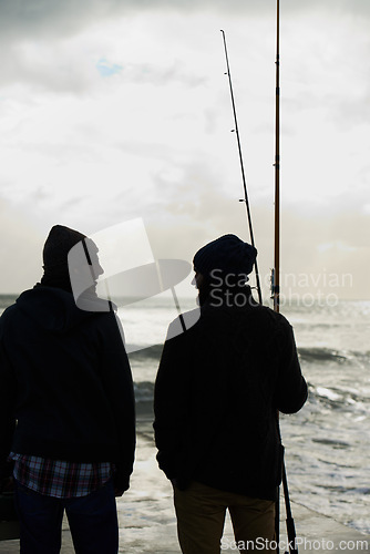 Image of Fishing, fisherman and men by ocean talking with rod, reel and equipment to catch fish for hobby. Friends, sports and people cast line for adventure on holiday, vacation or weekend together in nature