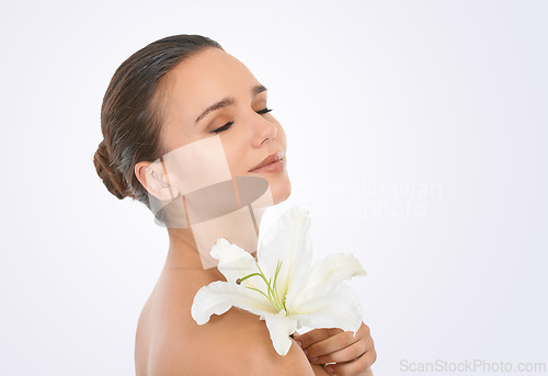 Image of Cosmetics, flower and beautiful woman in studio with glamour, glow and makeup face routine. Beauty, confident and young female person with floral plant for facial cosmetology by white background.