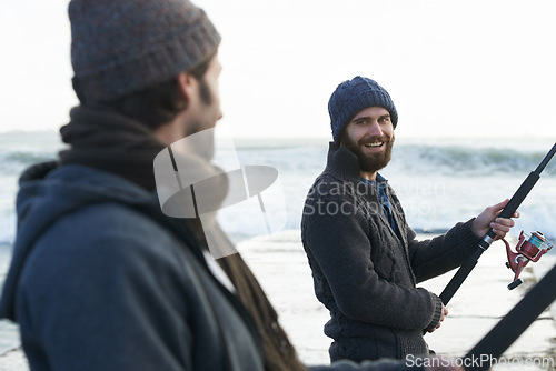 Image of People, fishing and friends at beach for hobby, relaxing and casting a line by ocean with gear. Men, fisherman and together on vacation or holiday, happy and bonding by waves and support on adventure