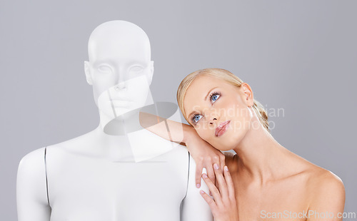 Image of Thinking, woman and mannequin with perfect beauty versus artificial standard, studio and facial wellness. Girl, doll and face in profile for cosmetics, plastic surgery or ideas on grey background.