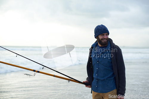 Image of Relax, fishing and man walking on beach with rods, nature and outdoor holiday adventure. Ocean, tools and fisherman with pole, smile and cloudy sky with waves on winter morning vacation at sea.