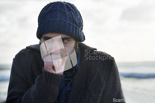 Image of Winter, breathing and beach with man, thinking and cold weather with waves and freezing. Person, ocean and guy with wool jersey and cap with early morning activity and nature with vacation and travel