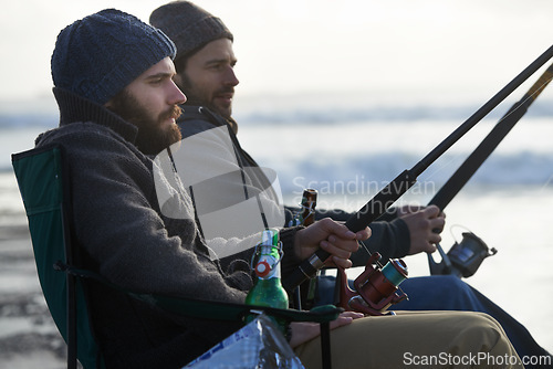 Image of Friends, men and fishing on beach in nature with rod, alcohol and relax on vacation, holiday or travel. Friendship, people and bonding in morning with overcast, sky and waves for activity or hobby