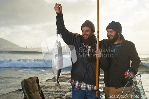 Image of Happy, people and fishing at ocean with pride for catch of tuna on holiday, travel or vacation. Fisherman, friends and smile holding fish and net in hand on adventure in nature with waves at sea