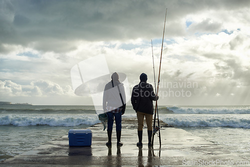 Image of Fishing, fisherman and back of friends on pier by ocean with rod, reel and equipment to catch fish for hobby. Nature, sports and men for bonding, fun and adventure on holiday, vacation and weekend