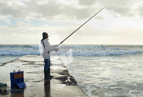 Image of Fishing, fisherman and man on pier by sea with rod, reel and equipment to catch fish for hobby. Nature, sports and person cast a line for recreation or adventure on holiday, vacation and weekend