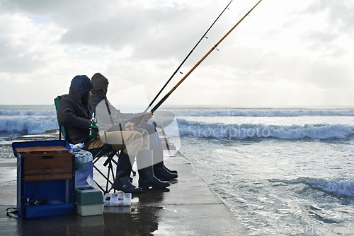 Image of Ocean, fishing rod and men outdoor in winter, leisure activity at beach or harbor with friends in nature for seafood. Travel, seascape and waves with fisherman, recreation or hobby in the cold