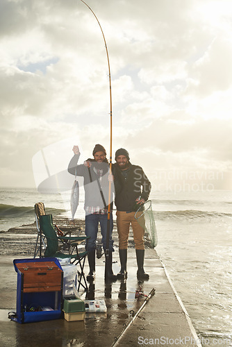 Image of Happy, portrait and people at ocean fishing with pride to catch tuna on pier at sunset. Fisherman, friends and smile holding fish in hand on adventure in nature at sea for holiday or vacation