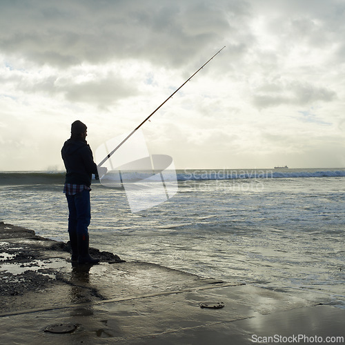 Image of Casting, fishing rod and man at a beach for water hobby, recreation or stress relief in nature. Pole, line and male fisherman at the ocean for travel, journey or fish sports adventure in Cape Town