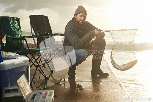 Image of Portrait, net and beach with man, fish and hobby with equipment, sunshine and weekend break. Person, ocean and guy with tools for activity and happiness with waves, shore and seaside with lens flare