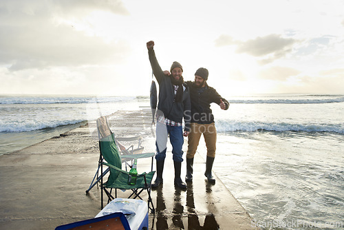 Image of Happy, portrait and people fishing at ocean with pride for tuna catch on pier at sunset. Fisherman, friends and smile holding fish in hand with success in nature at sea on holiday or vacation