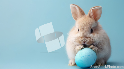 Image of Rabbit with blue egg on blue background, happy Easter