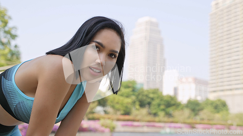 Image of Active Woman Exercising in the Park with Cityscape