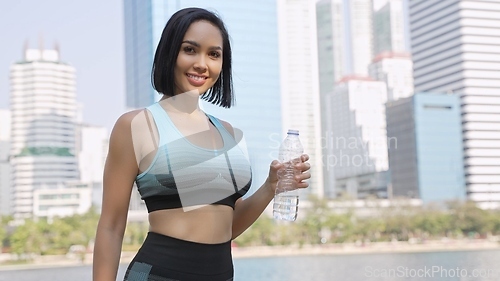 Image of Active Woman Holding Water Bottle in Urban Park