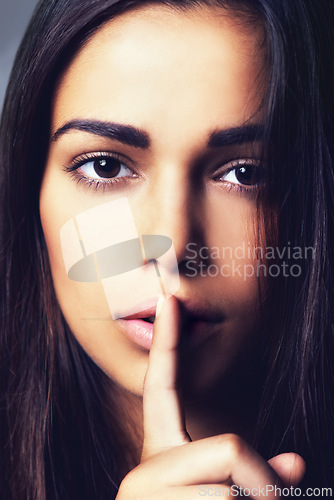 Image of Woman, finger and quiet for mystery in studio portrait, secret and confidential information or emoji. Female person, private and shush icon on gray background, closeup and silence for announcement
