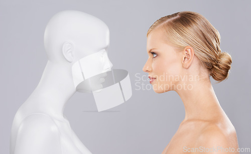 Image of Studio, woman and mannequin with beauty clone versus artificial standard, perfect and facial wellness. Girl, doll and face in profile for cosmetics, plastic surgery or makeup on grey background.