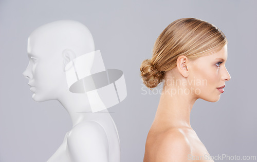 Image of Studio, woman and profile of mannequin with beauty versus artificial standard, perfect and facial wellness. Girl, doll and clone of face for cosmetics, plastic surgery or makeup on grey background.